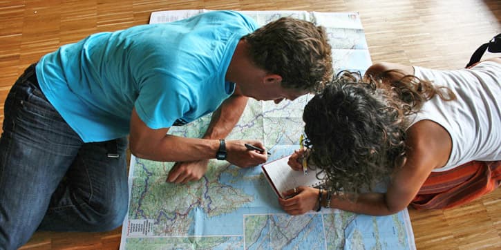 Two people drawing an Andalusia Travel Itinerary on a map