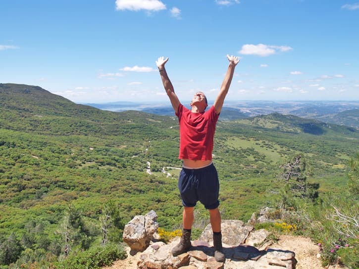 A man on top of a mountain with an expression of wellbeing